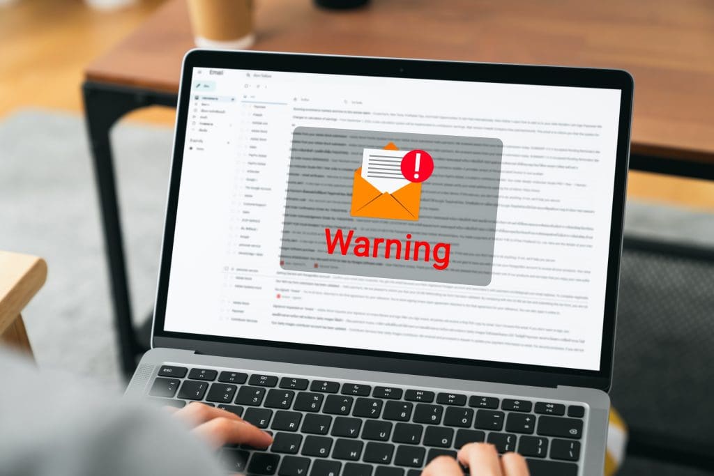 A laptop screen opened to an email inbox with a big warning box.