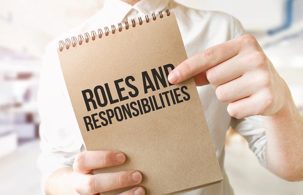 A person holding a tablet that reads “Roles and Responsibilities.”