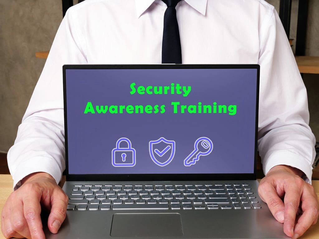 A person holding a laptop with a screen facing the reader that reads “Security Awareness Training.”