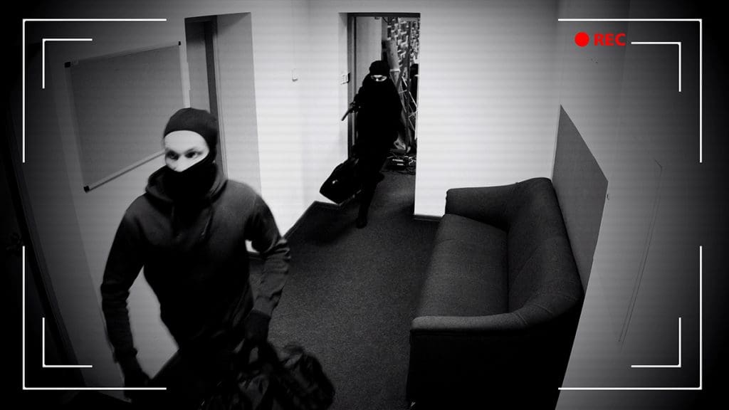 A security camera capturing two robbers walking down a hallway.