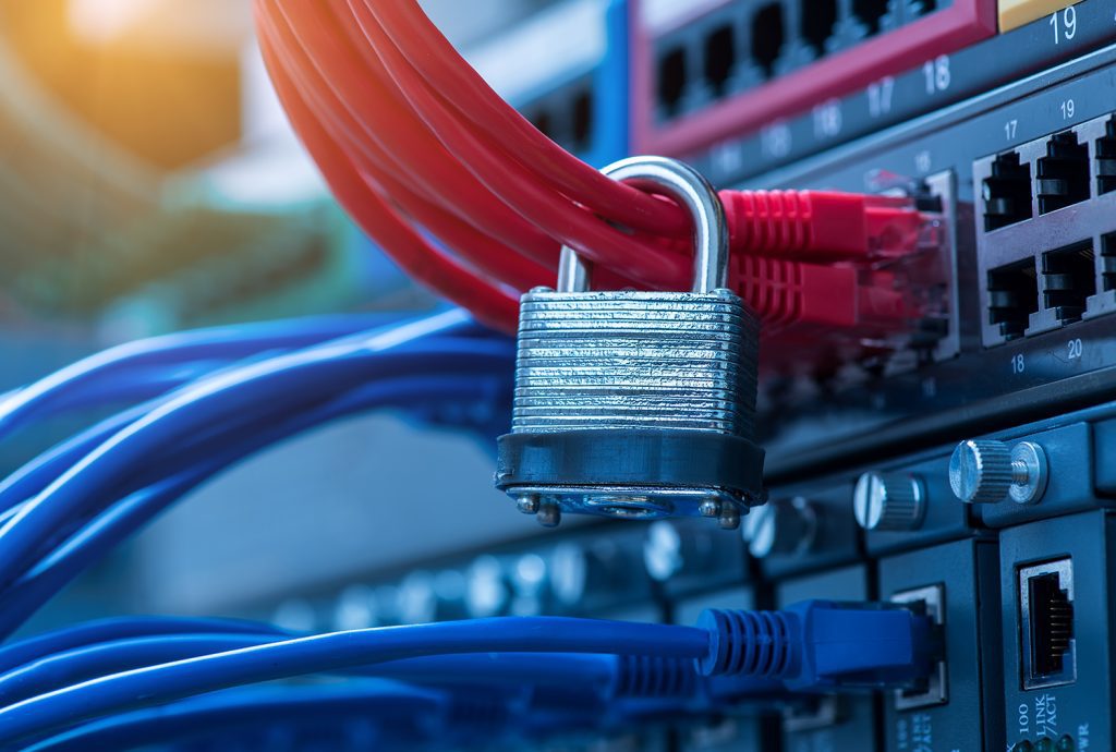 The back of a data center with ethernet cables coming out of it and a padlock around them.