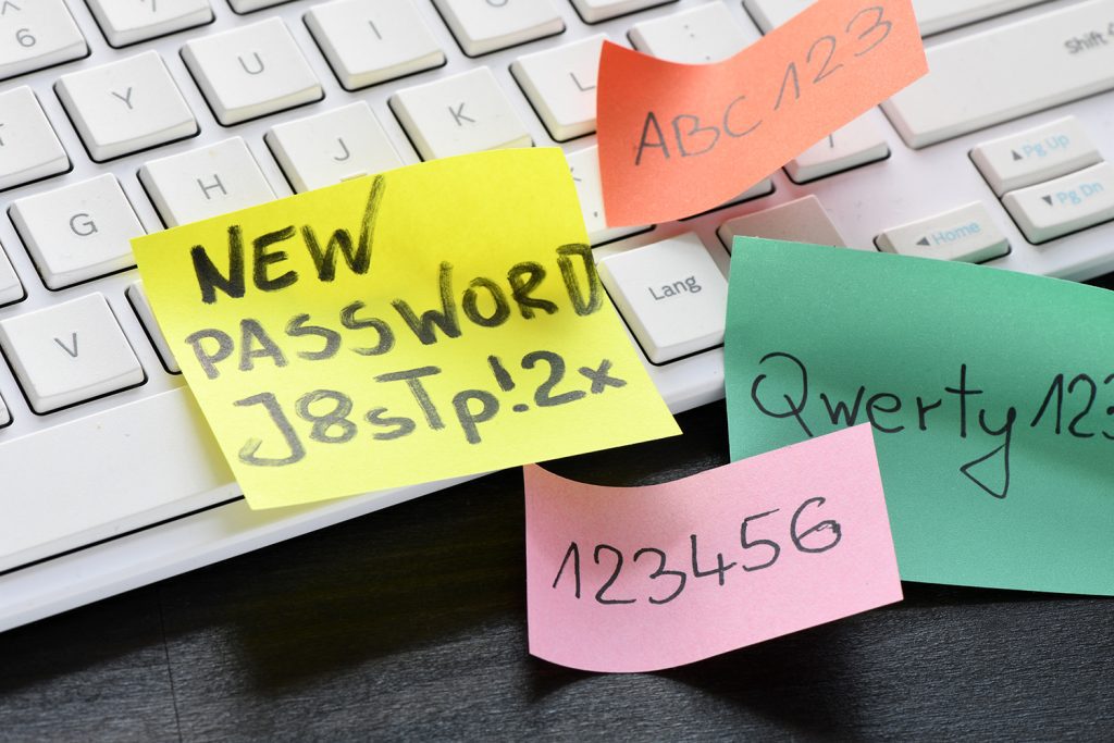 A computer keyboard with various sticky notes of weak passwords.